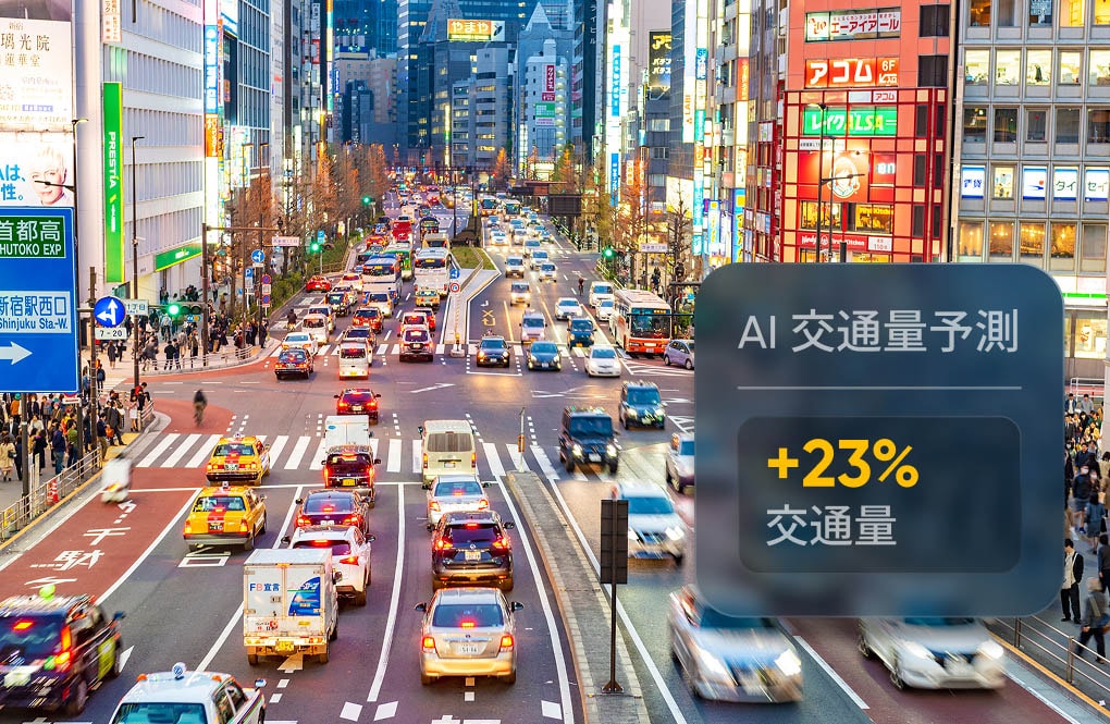 Busy urban street scene with heavy traffic and bright city lights, featuring a 23% traffic increase prediction overlay in Japanese.
