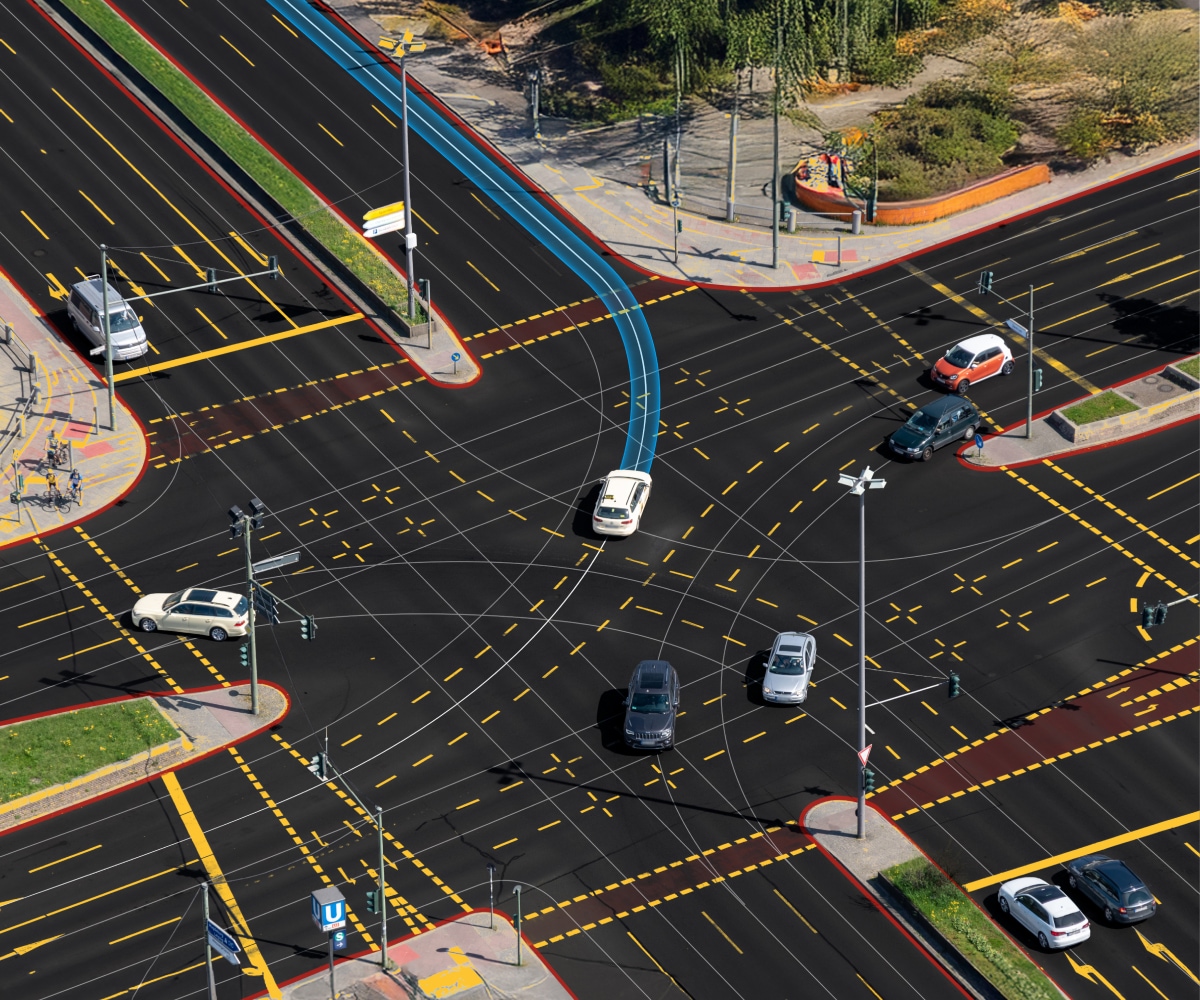 Aerial view of a busy intersection with multiple cars, marked lanes, and painted traffic signs.
