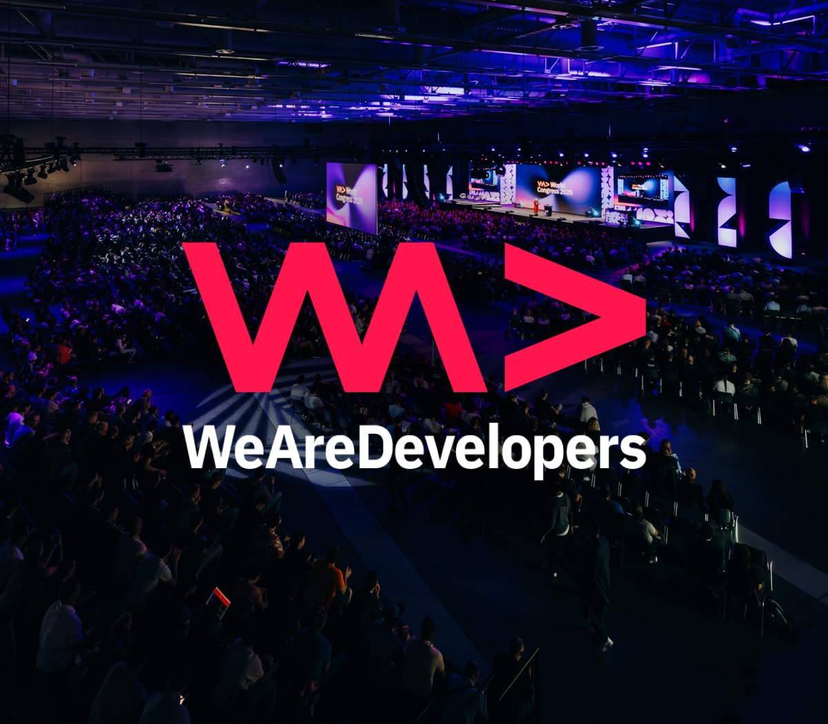 Large conference venue filled with attendees, featuring bright stage lights, and a logo "WeAreDevelopers" prominently displayed.