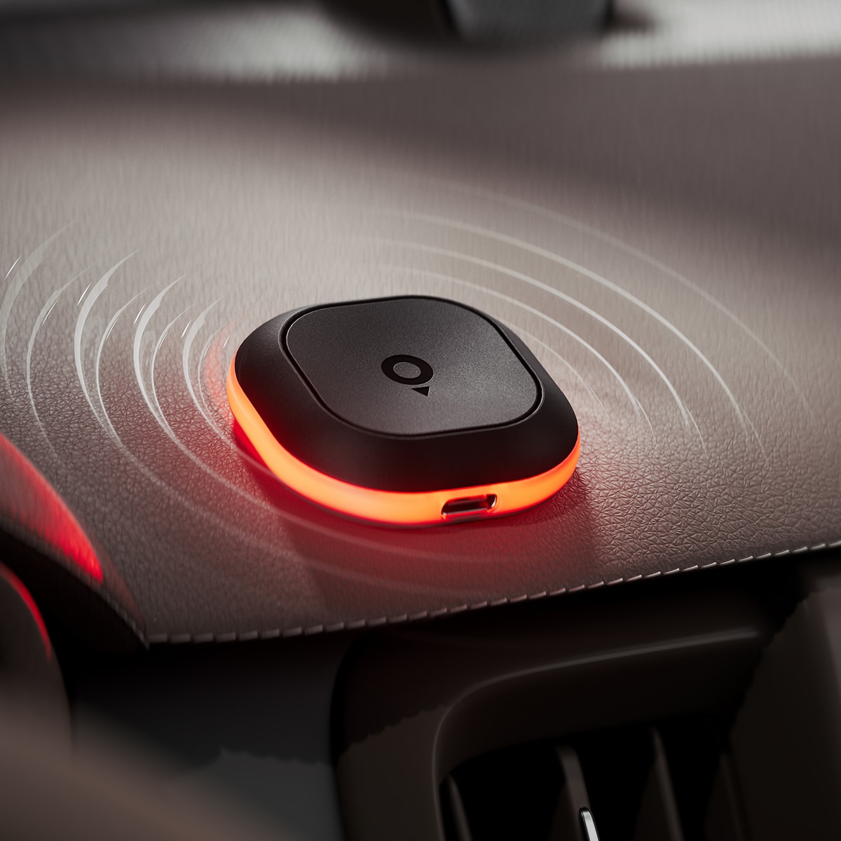 Tom by TomTom device with a glowing red edge rests on a car dashboard, emitting circular wave patterns.