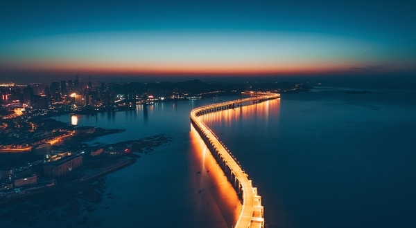 A picture of a well lit highway bridge extending to the horizon at dusk