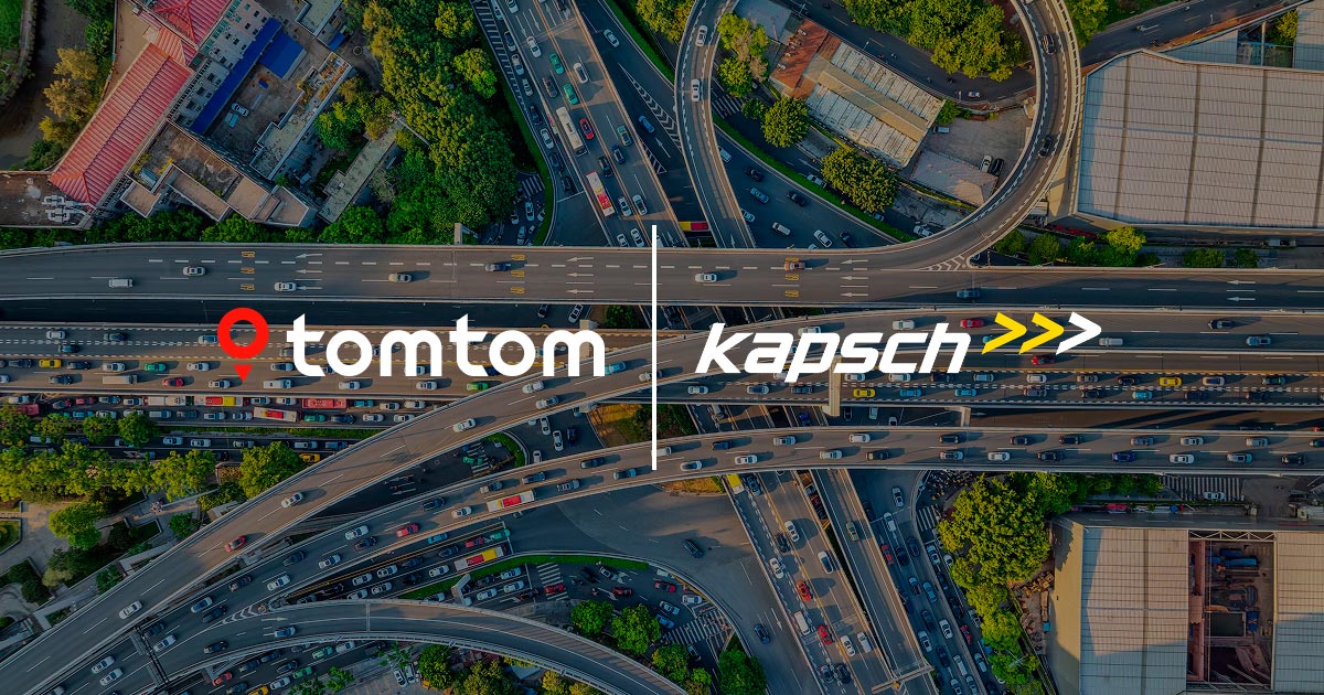 Aerial view of a busy highway interchange with numerous cars, overlaid with logos of TomTom and Kapsch against a clear sky backdrop.