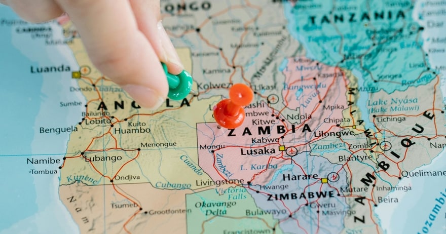 A hand placing map pins in a map of Africa