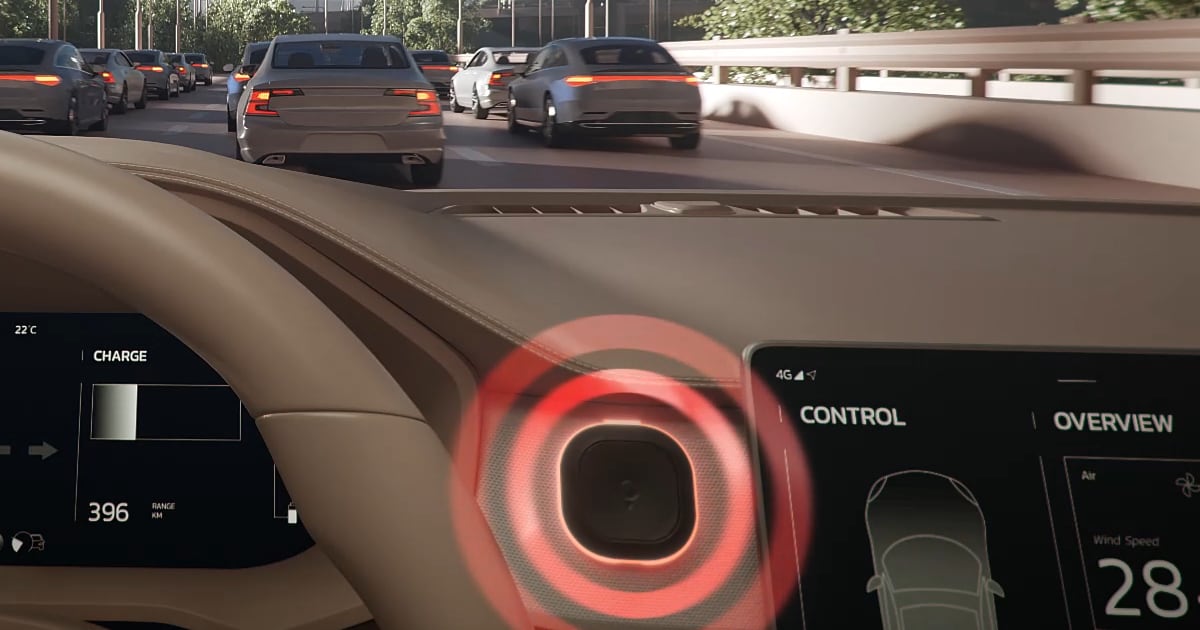 Car dashboard showing a speedometer and control screen, with tom by tomtom device showing red lights. Traffic is visible through the windshield on a sunny day.