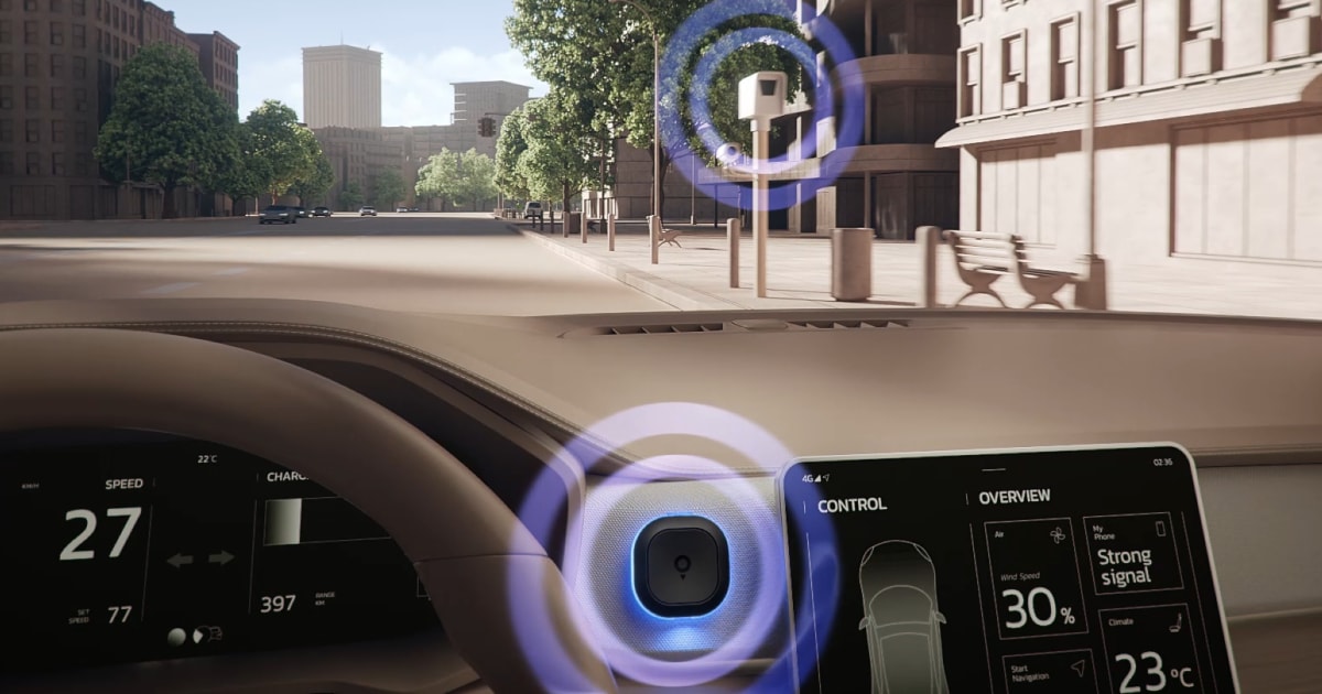 View from a car's interior with digital displays showing speed and traffic signals, driving through a city street with trees and buildings.