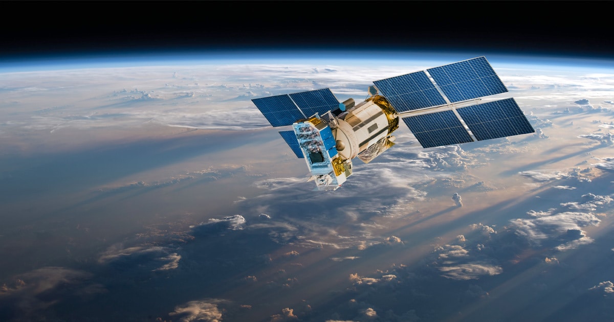 A satellite with solar panels orbits Earth against a backdrop of clouds.