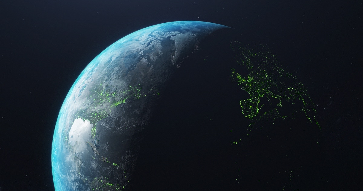 A crescent view of Earth from space, with visible green lights on the dark side, contrasting against the planet's bright, illuminated surface.
