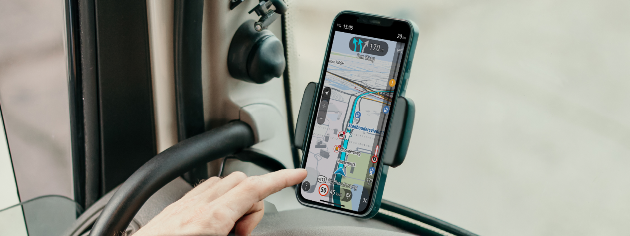 Smartphone mounted in a car displays GO Expert app with a map and directions. A hand is pointing at the screen.