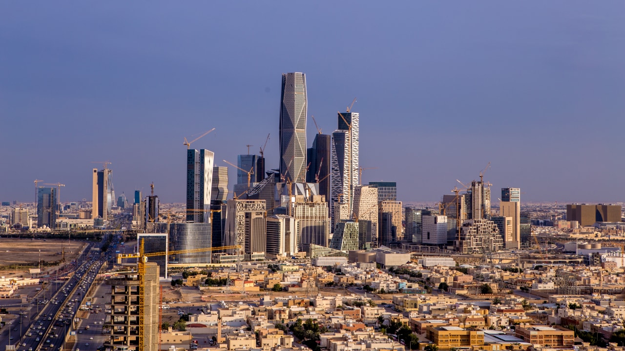 Aerial view of Riyadh's skyline featuring modern skyscrapers under a clear blue sky.