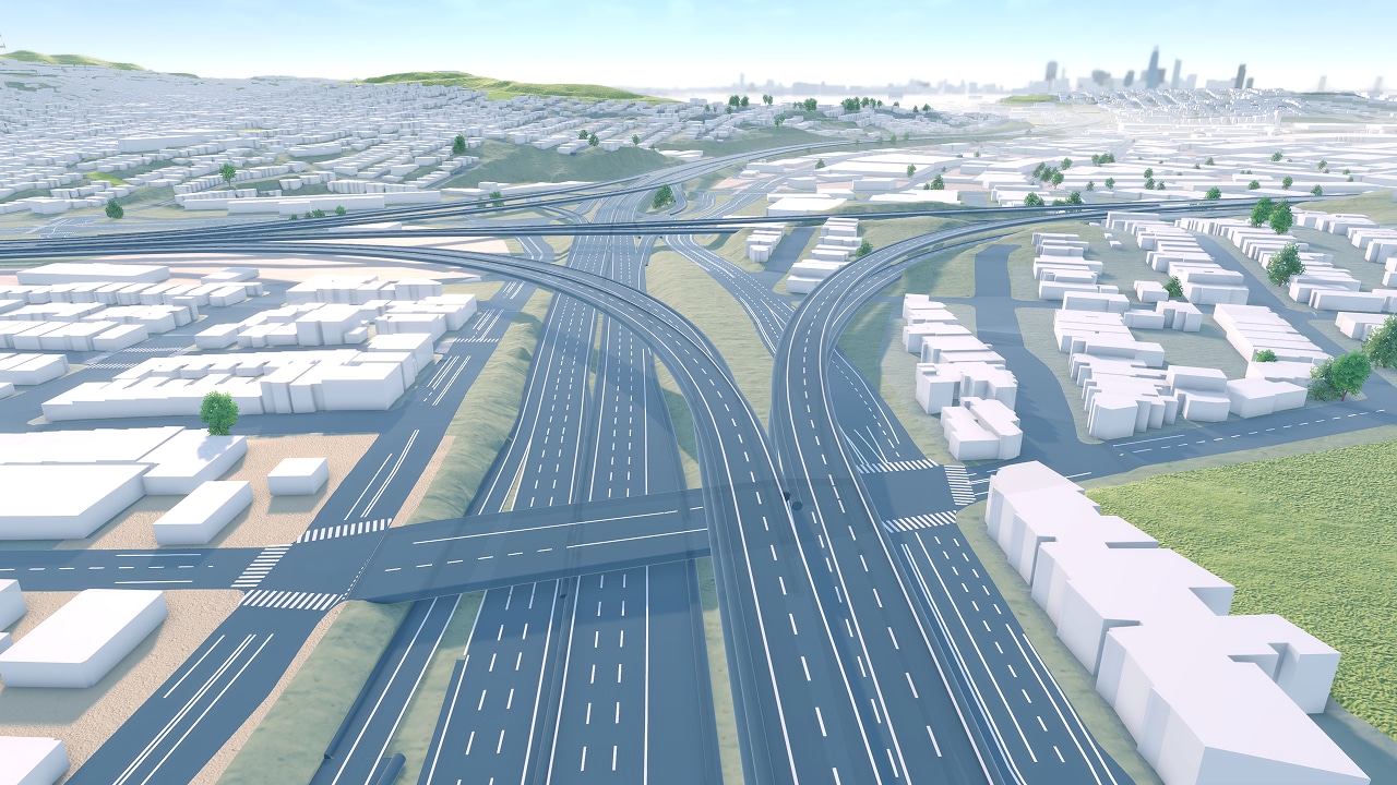 Aerial view of a sprawling highway interchange surrounded by buildings, with a city skyline visible in the distance.