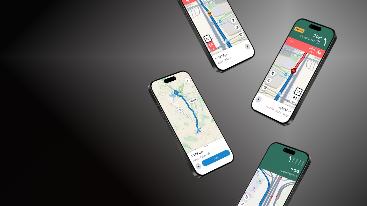 Four smartphones displaying different navigation apps with maps and routes on dark background.