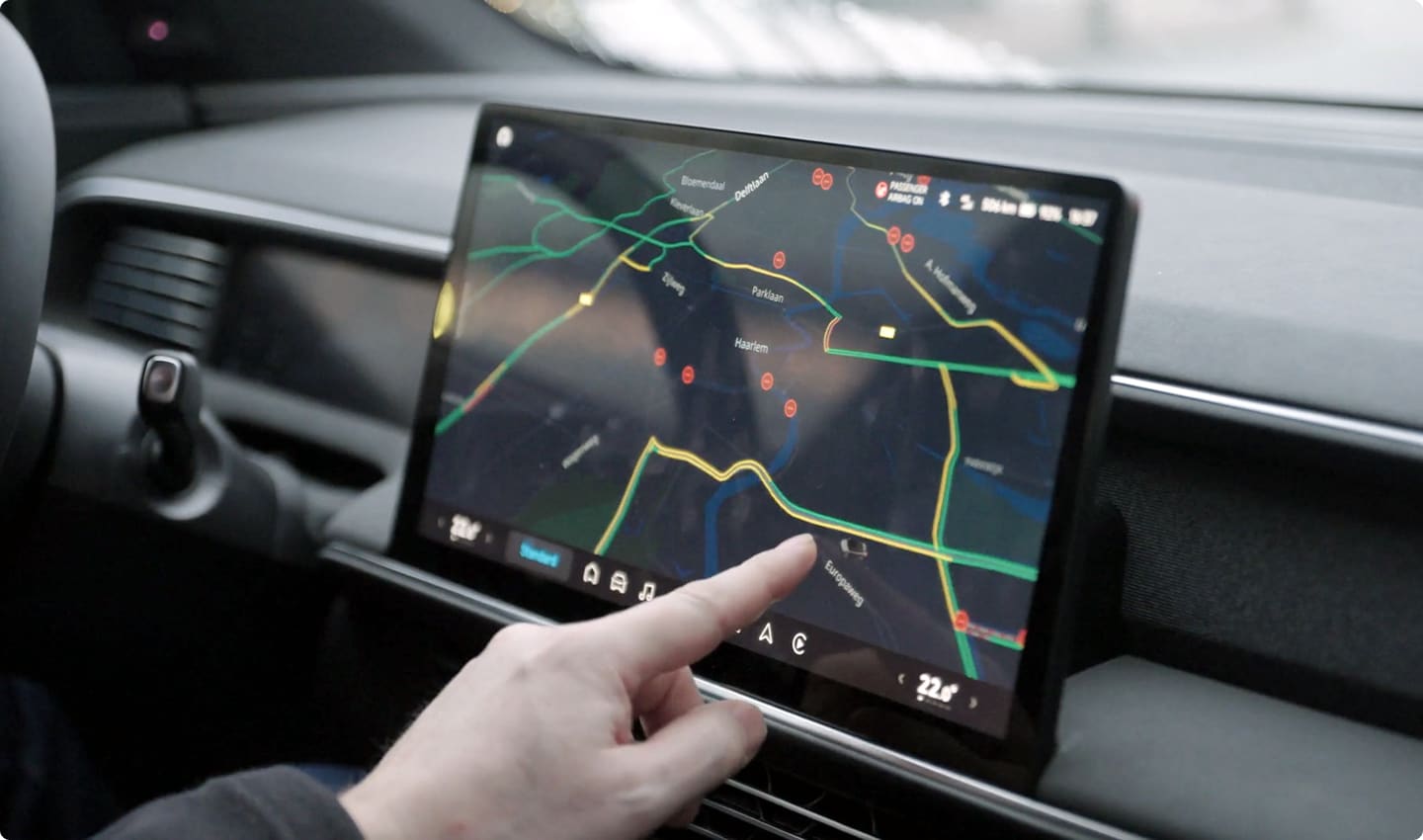An image showing a hand pointing at a development navigation in a car