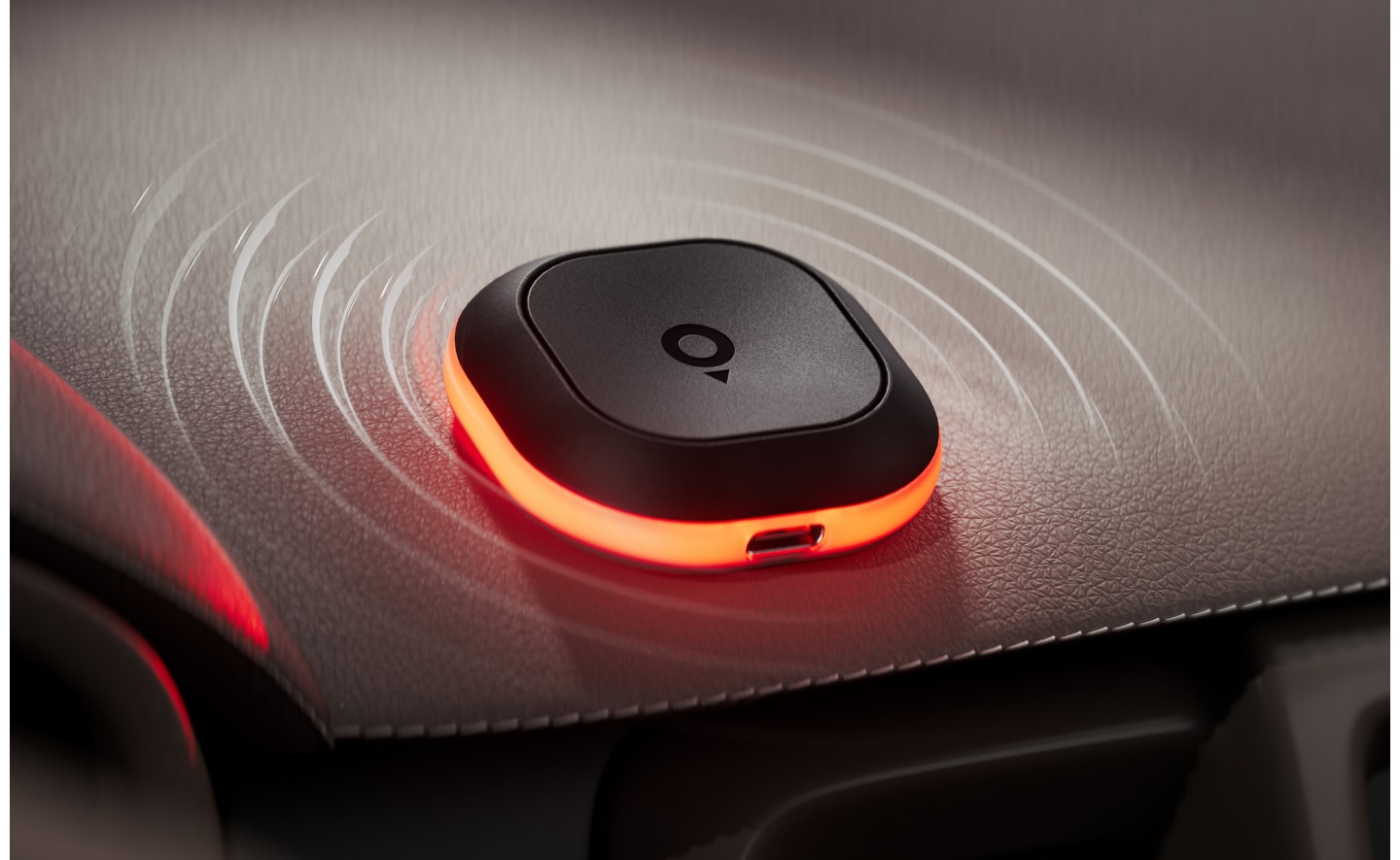 A black device with a glowing red ring sits on a textured surface, emitting circular wave patterns, suggesting connectivity or signal transmission.