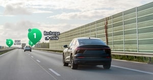 Electric car driving on a highway with digital markers showing nearby charging stations, highlighting a 150 kW recharge point.