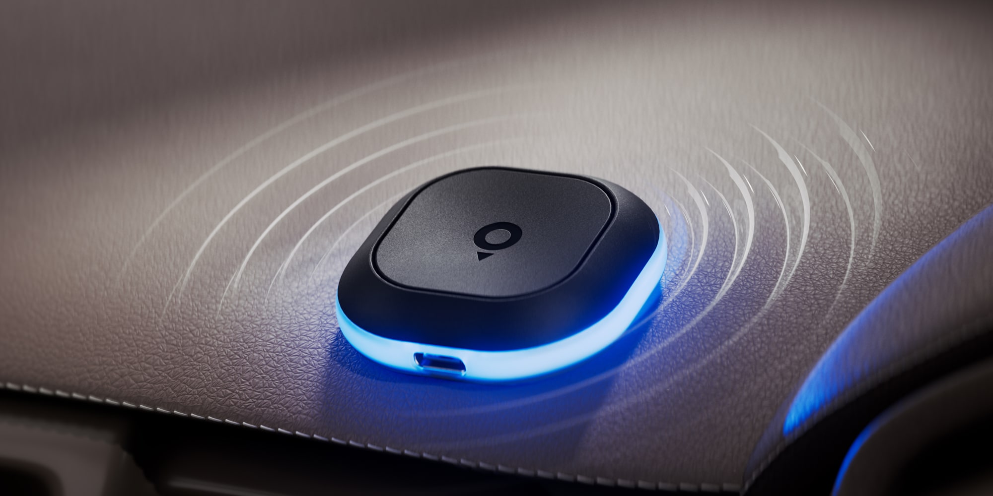 tom by tomtom device with a glowing blue edge emits signal waves on a textured surface.