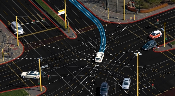 Aerial view of a busy intersection with cars and marked lanes, featuring blue directional arrows and dotted lines against the dark road.