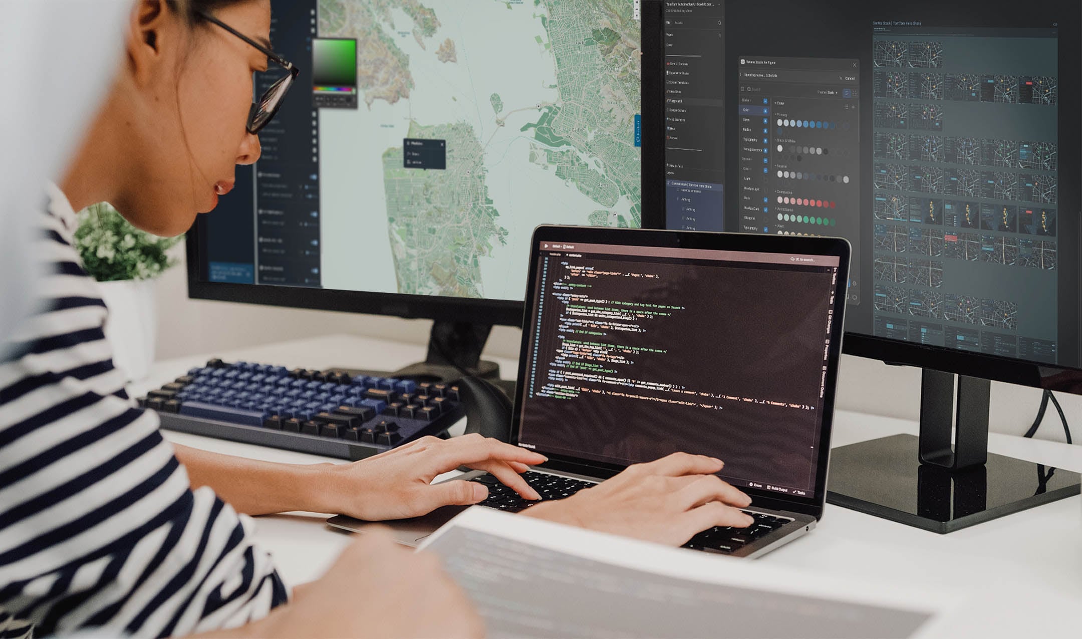 Person working at a desk with a laptop showing maps and data visuals.