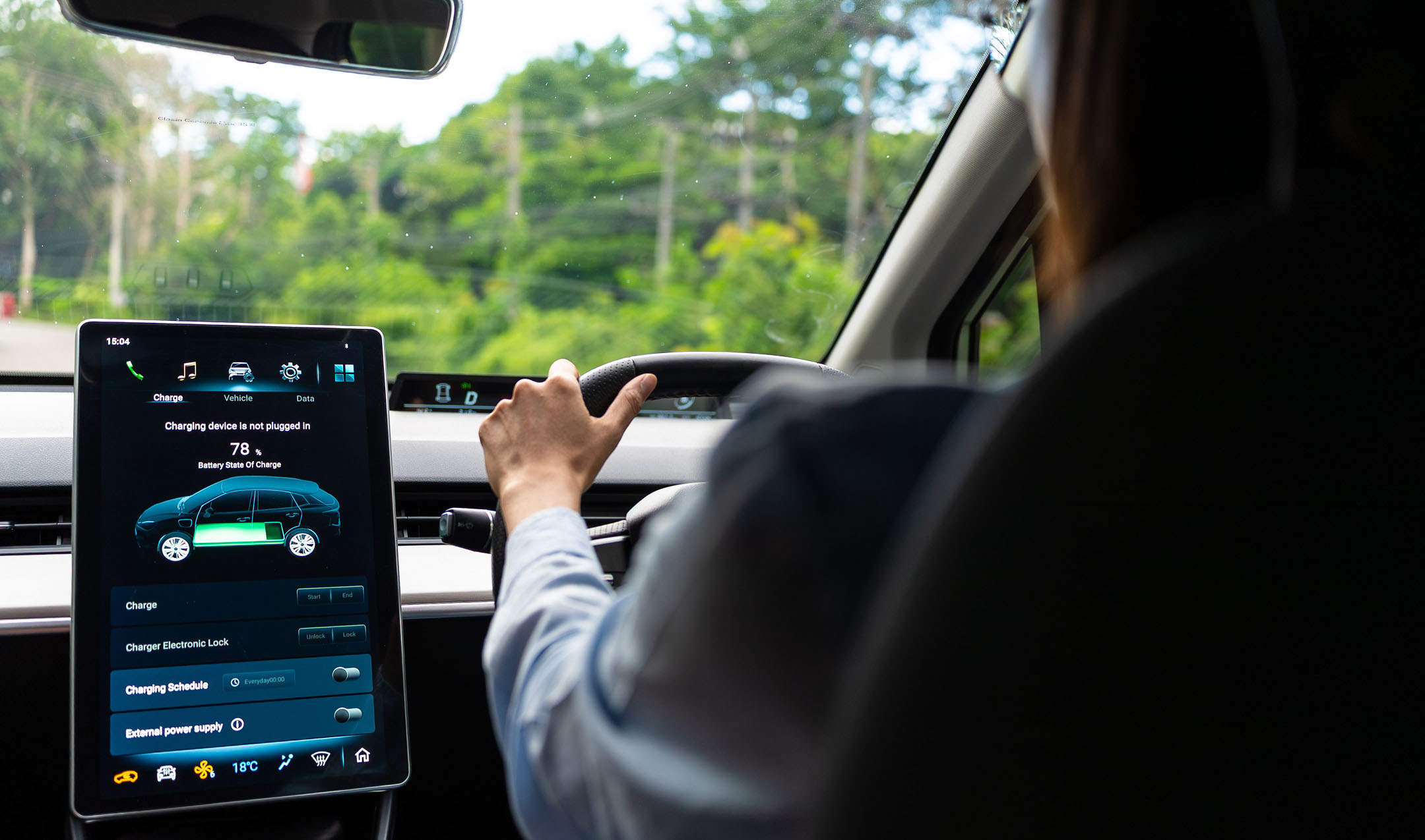 Person driving a car with a digital display showing battery state of charge at 78%. The car's green, leafy scenery can be seen through the windshield.