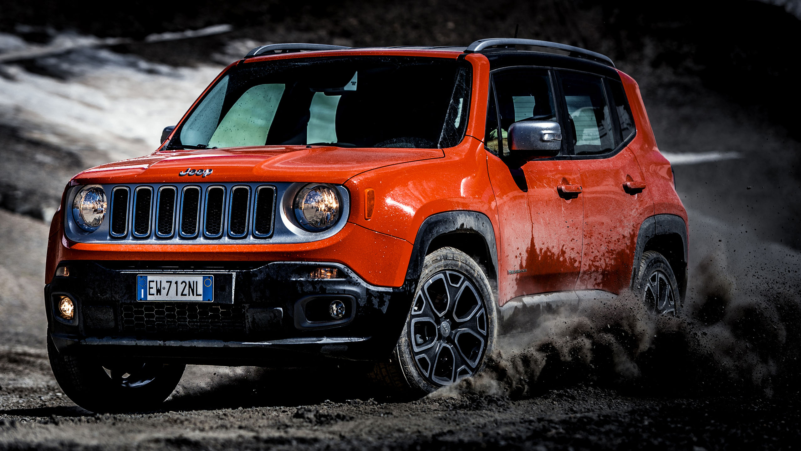 An red Jeep Renegade driving through dirt.