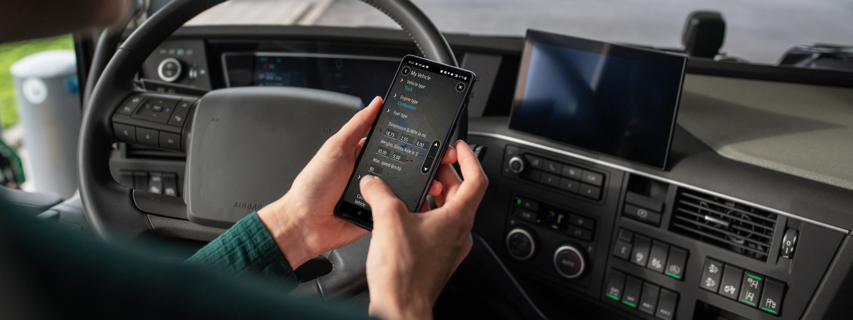 Person using a GO Expert app inside a truck, displaying navigation and vehicle data, with a steering wheel and dashboard visible.
